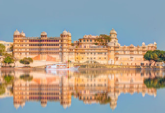 El agua tranquila del lago Pichola refleja el Palacio de la ciudad de Udaipur en todo su esplendor. Durante un período de 400 años, dos maharanas presidieron su reino desde este complejo, Udaipur, Rajasthan © Muratart