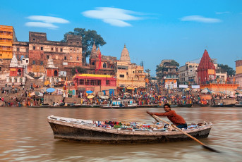 Un barquero rema con su mercancía en el río Ganges frente a uno de los 88 ghats sagrados de Varanasi © Lena Serditova