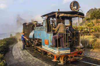 El tren histórico de vía estrecha de Darjeeling en una parada en la ruta. El conductor le pone aceite a la máquina - Imagen de Anandoart