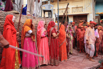 Mujeres llevando largos palos para vencer a los hombres como un ritual en la celebración Lathmar Holi (Festival de color) en Nandgaon, India - Imagen de AJP