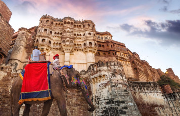 Pareja de turistas sobre elefante con decorado indio en la histórica fortaleza de Mehrangarh Jodhpur al atardecer, Rajasthan © Roop_Dey / Shutterstock