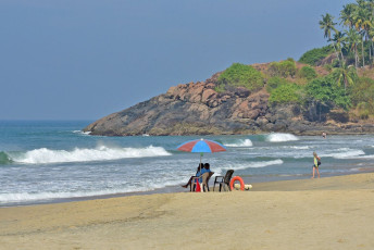 Salvavidas sentados bajo una sombrilla en la playa en un día caluroso y soleado, Kovalam - Imagen de Ajayptp