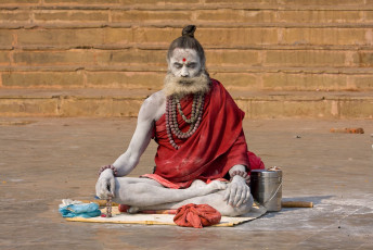 Naga baba sadhu se sienta a orillas del Ganges en Varanasi, India © OlegD / Shutterstock