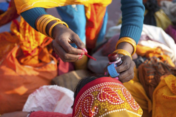 Una señora sahdu pinta el bindi en la cara de una mujer después de un baño en el río Ganges como parte de la bendición - Imagen de Wkok