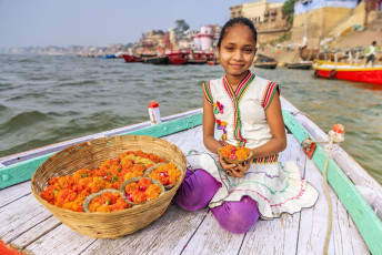 Niña vendiendo velas de flor en el barco, Río Ganges, Varanasi – Imagen por Bartosz Hadyniak