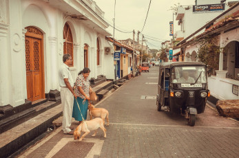 Lugareños con su perro paseando junto a tuk-tuk conduciendo en la histórica ciudad de Galle, Sri Lanka © Radiokukka