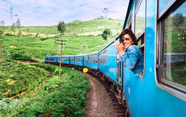 Mujer feliz y sonriente mira por la ventana viajando en tren en la ruta de tren más pintoresca hacia Nuwara Eliya, Sri Lanka ©solovyova