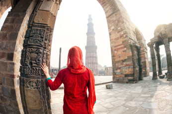 Mujer en traje rojo mirando la torre Qutub Minar en Delhi, India © Pikoso.kz / Shutterstock