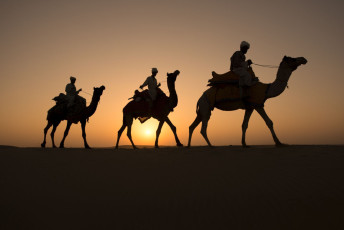 Tres camelleros indios en las dunas del desierto de Thar al atardecer, Jaisalmer, Rajasthan, India © CrispyPork / Shutterstock