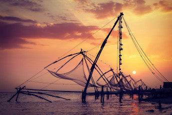 Redes de pesca chinas bajo la puesta del sol, Fuerte Kochin, Kochi, Kerala, India © DR Travel Photo and Video / Shutterstock