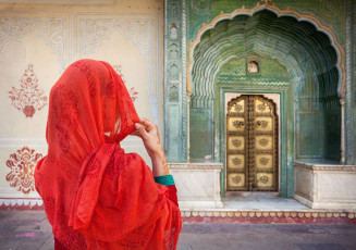 Mujer con pañuelo rojo mirando la puerta verde en el City Palace Museum de Jaipur, Rajasthan, India © Pikoso.kz / Shutterstock