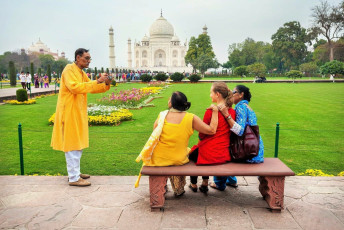 Familia india tomando una foto con extranjeros en el banco en el jardín frente al Taj Mahal, Agra - Foto por Pikoso.kz