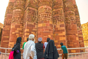 Familia musulmana estudiando la inscripción Kufi de Qutb Minar, torre de la victoria construida alrededor de 1192 por Qutb-ud-din Aibak, el primer gobernante del Sultanato de Delhi, New Delhi, India © panoglobe / Shutterstock