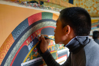Joven pintor con mandala tradicional y símbolos religiosos en una escuela de artesanía en Bhutan © angela Meier / Shutterstock