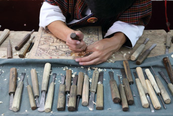 Manos de un aprendiz tallador trabajando en un panel de madera en Thimphu, Bhutan © Louis W / Shutterstock