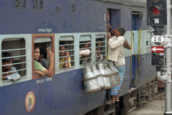 Hombres colgados de la puerta de un tren en movimiento. Lecheras colgando de las ventanas, India - Imagen de JeremyRichards