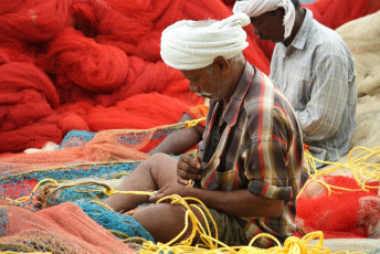 Pescadores tejiendo redes en su tiempo libre y se preparan para la siguiente ronda de pesca marítima en el mar Arábigo en Mararikulam, Kerala - Imagen de AJP