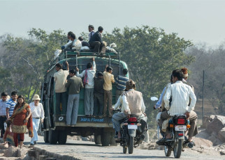 Autobús de transporte público sobrecargado llevando la gente en la parte superior y colgando en la parte de atrás - Imagen de Claudine Van Massenhove