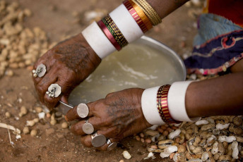 Mujer Lambadi / banjara con manos adornadas con joyería hechas de monedas. Ella está lavando su plato después de comer - Imagen de vdhya