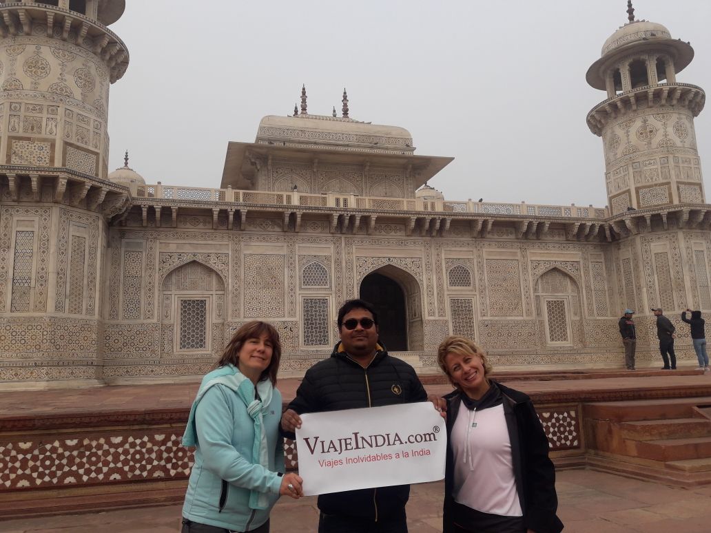 La familia Andrea Susanna y Alejandra Meleghelli, de Argentina, posando con la pancarta de nuestra empresa delante de Itmad-ud-Daula (Baby Taj) en Agra. Reservaron el Tour Cultura de Rajastán con Khajuraho y varanasi